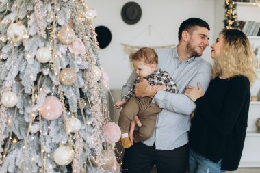Anne ve babanın mutlu aile portresi ve evde birlikte Noel 'i kutlayan kıvırcık oğlan. Yeni yıl arifesi konsepti.