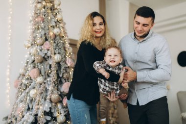 Anne ve babanın mutlu aile portresi ve evde birlikte Noel 'i kutlayan kıvırcık oğlan. Yeni yıl arifesi konsepti.