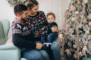 Anne ve babanın mutlu aile portresi ve evde birlikte Noel 'i kutlayan kıvırcık oğlan. Yeni yıl arifesi konsepti.