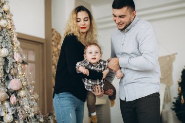 Anne ve babanın mutlu aile portresi ve evde birlikte Noel 'i kutlayan kıvırcık oğlan. Yeni yıl arifesi konsepti.