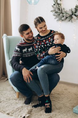 Anne ve babanın mutlu aile portresi ve evde birlikte Noel 'i kutlayan kıvırcık oğlan. Yeni yıl arifesi konsepti.