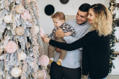 Anne ve babanın mutlu aile portresi ve evde birlikte Noel 'i kutlayan kıvırcık oğlan. Yeni yıl arifesi konsepti.