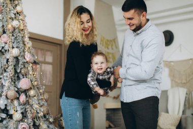 Anne ve babanın mutlu aile portresi ve evde birlikte Noel 'i kutlayan kıvırcık oğlan. Yeni yıl arifesi konsepti.
