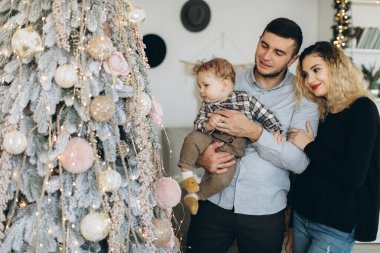 Anne ve babanın mutlu aile portresi ve evde birlikte Noel 'i kutlayan kıvırcık oğlan. Yeni yıl arifesi konsepti.