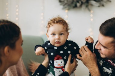 Anne ve babanın mutlu aile portresi ve evde birlikte Noel 'i kutlayan kıvırcık oğlan. Yeni yıl arifesi konsepti.