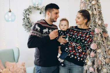 Anne ve babanın mutlu aile portresi ve evde birlikte Noel 'i kutlayan kıvırcık oğlan. Yeni yıl arifesi konsepti.