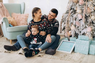 Anne ve babanın mutlu aile portresi ve evde birlikte Noel 'i kutlayan kıvırcık oğlan. Yeni yıl arifesi konsepti.