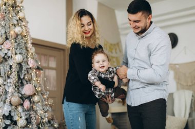 Anne ve babanın mutlu aile portresi ve evde birlikte Noel 'i kutlayan kıvırcık oğlan. Yeni yıl arifesi konsepti.