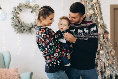 Anne ve babanın mutlu aile portresi ve evde birlikte Noel 'i kutlayan kıvırcık oğlan. Yeni yıl arifesi konsepti.