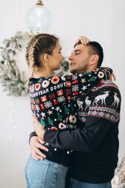 Geleneksel süveter giyen mutlu çift evde Noel ağacı süslüyorlar.