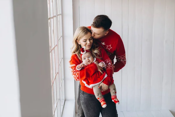 幸せな家族のお母さんと小さな娘で赤伝統的なクリスマス衣装一緒に過ごす時間で光の木製の部屋近くのウィンドウ コピースペース — ストック写真