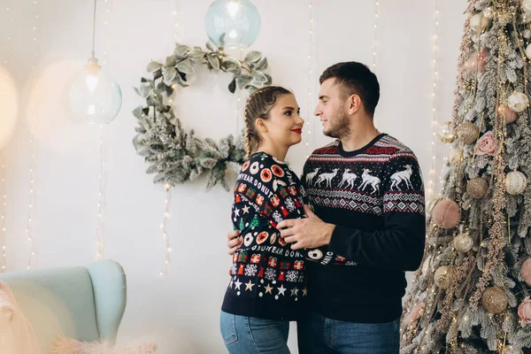 ハッピーカップルで伝統的なセーター飾るクリスマスツリー一緒に自宅 — ストック写真