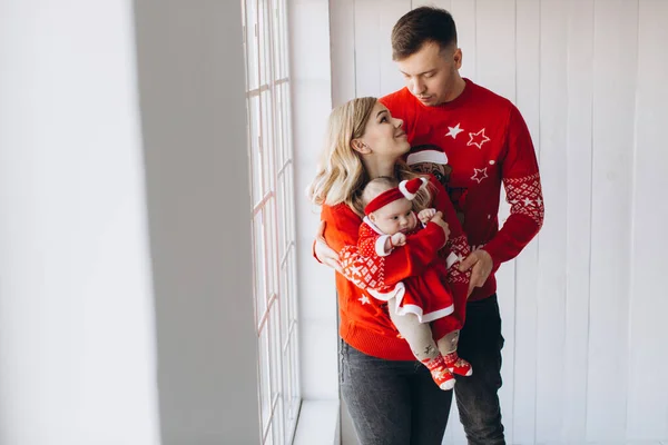 幸せな家族のお母さんと小さな娘で赤伝統的なクリスマス衣装一緒に過ごす時間で光の木製の部屋近くのウィンドウ コピースペース — ストック写真
