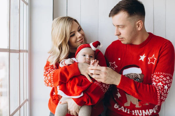 幸福家庭的画像妈妈爸爸和小女儿穿着红色的传统圣诞服装 在靠近窗户的小木屋里共度时光 复制空间 — 图库照片