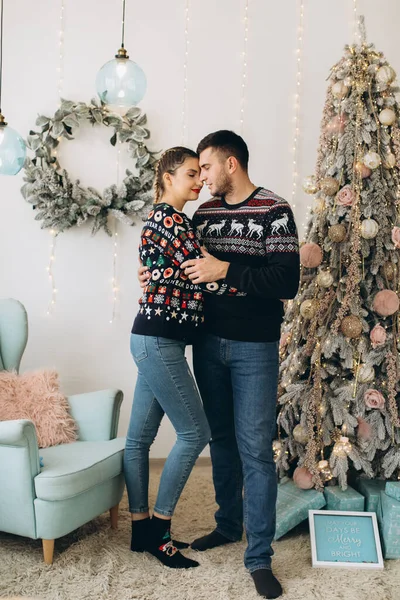 ハッピーカップルで伝統的なセーター飾るクリスマスツリー一緒に自宅 — ストック写真