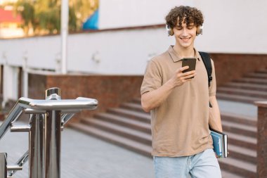 Çekici kıvırcık erkek üniversitesi ya da kampüste telefonla dolaşan üniversite öğrencisi.