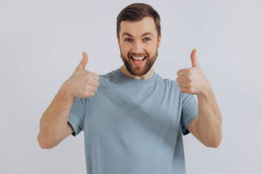 Mavi tişörtlü, modern sakallı orta yaşlı bir adamın portresi beyaz arka planda güzel duygular gösteriyor.
