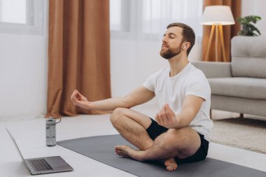 Karantinada sakin olun. Millennial elemanı antrenörle internetten laptopla meditasyon yapıyor. Boş alan.