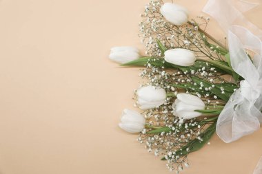 Beyaz laleler ve bej arka planda çingene çiçekleri. Anneler Günü, doğum günü kutlaması konsepti. Uzayı metin için kopyala. Model