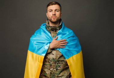 Ukrayna bayrağıyla bağlı cesur bir Ukraynalı askerin portresi ve el ele tutuşan bir kalp, özgürlük konsepti