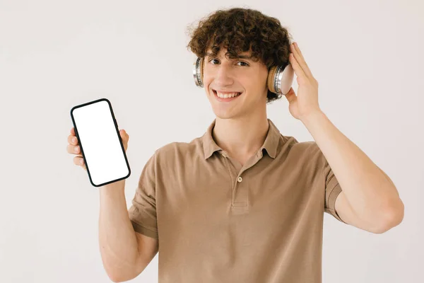 Kulaklıklı Çekici Bir Gencin Portresi Elinde Akıllı Telefon Beyaz Ekran — Stok fotoğraf