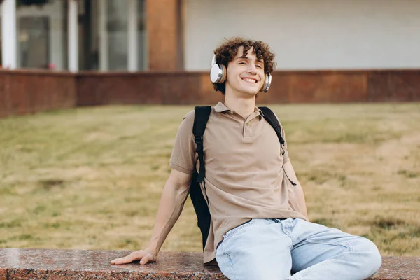 Concept of e-learning, distance study or remote learning concept, Young happy curly hair school guy, college or university student with backpack and headphones