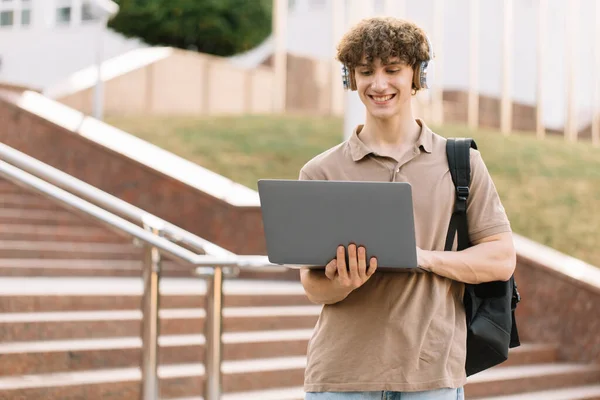 电子学习 远程学习或远程学习的概念 年轻快乐的卷发学生 大学生 带着背包和耳机 站在大学的台阶上 — 图库照片