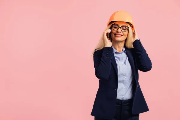 Architect woman in glasses use mobile phone call with engineer or project manager on the pink background