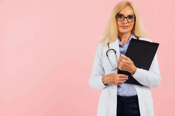 Dojrzałe Kobieta Lekarz Okulary Stetoskop Gospodarstwa Folderu Różowym Tle Miejsca — Zdjęcie stockowe