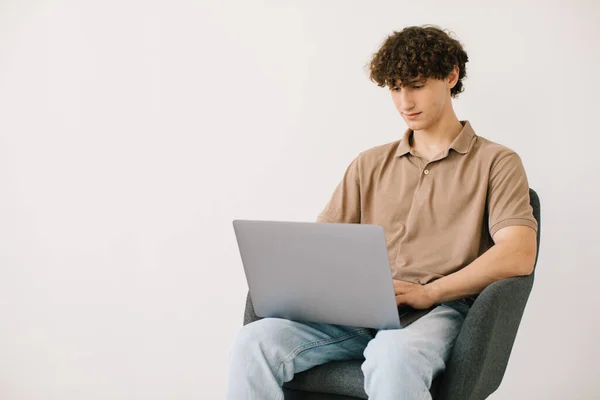 Jovem Atraente Usando Laptop Enquanto Sentado Poltrona Contra Parede Branca — Fotografia de Stock