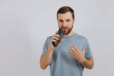 Kulaklıkla dans eden mutlu sakallı adam, kulaklıkla müzik dinliyor, cep telefonu tutuyor ve gülümsüyor.