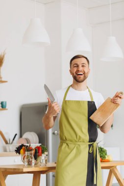 Mutfakta mutfak tahtası ve bıçak tutan mutlu adamın portresi..