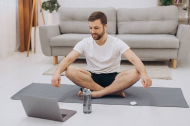 Karantinada sakin olun. Millennial elemanı antrenörle internetten laptopla meditasyon yapıyor. Boş alan.