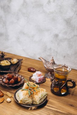 Ahşap bir masada kurutulmuş hurma ve çay. Geleneksel Arap yemekleri, saksılar ve hurma ağaçları. Ramazan Kareem, Bayram Mübarek kavramı. Boşluğu kopyala