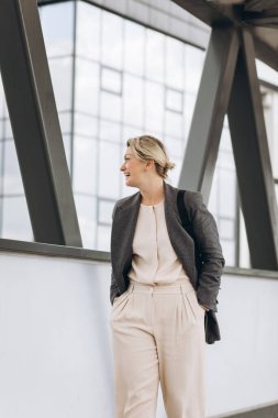 Olgun bir iş kadınının portresi modern şehir geçmişinde duygularla gülümsüyor.