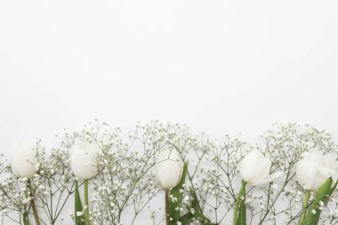 Beyaz laleler ve beyaz arka planda çingene çiçekleri. Anneler Günü, doğum günü kutlaması konsepti. Metin için alanı kopyala