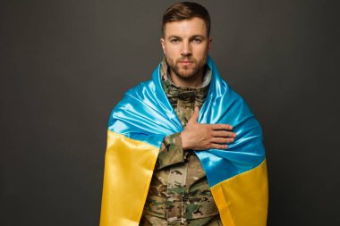 Ukrayna bayrağıyla bağlı cesur bir Ukraynalı askerin portresi ve el ele tutuşan bir kalp, özgürlük konsepti