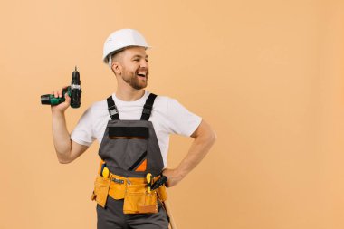 Evde elinde bej arka planda tornavida tutan olumlu bir erkek tamirci var.