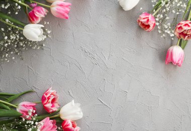 Pembe laleler ve zarif gri taştan arka planda beyaz çigila çiçekleri. Anneler Günü, doğum günü kutlaması konsepti. Metin için alanı kopyala