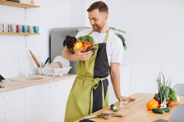 Mutfakta elinde taze sebze tabağı tutan mutlu bir adamın portresi.