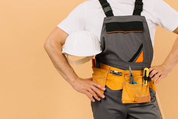 Мужчина строитель, держащий шлем на бежевом фоне