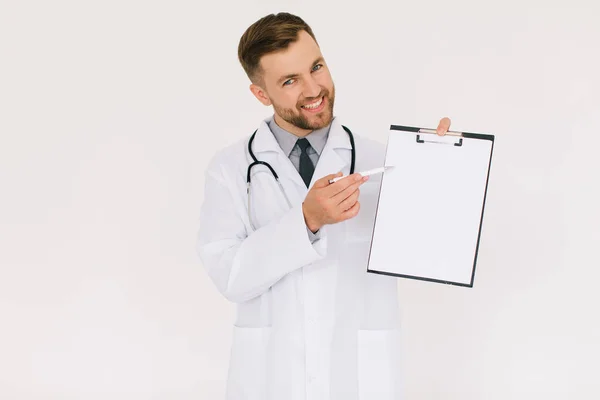 フォルダを持つ幸せな男性医師は 白い背景にコピースペースに何かを示しています — ストック写真