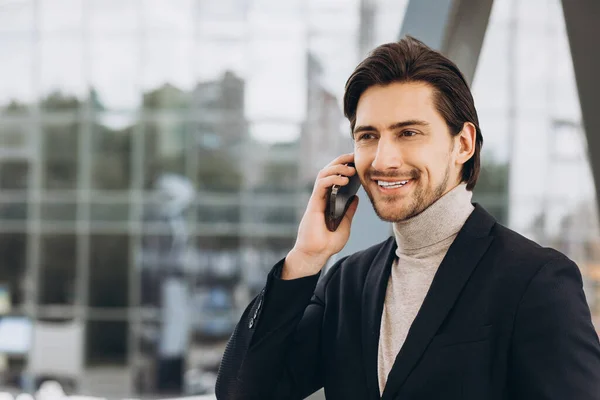 在城市建筑和办公室的背景下 穿着西装的英俊的现代男性商人的画像 通过电话交谈 微笑着 — 图库照片