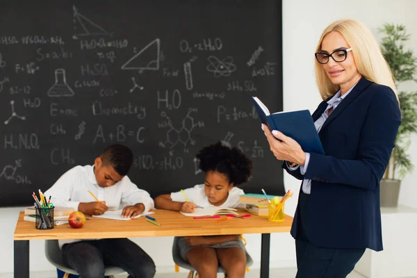教室や学童を背景に立つ女教師の肖像 — ストック写真