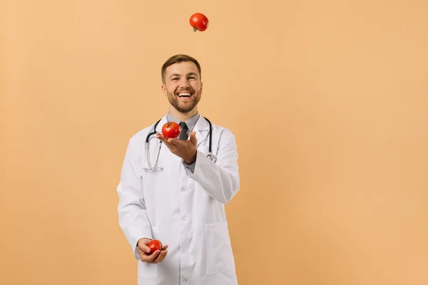 Mužský Nutriční Lékař Stetoskopem Úsměvem Žonglování Rajčat Béžovém Pozadí Dietní — Stock fotografie