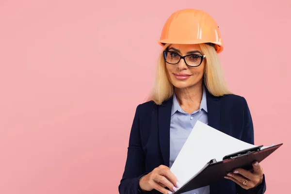 有魅力的成熟女建筑师或戴眼镜的女工程师的肖像用带有粉色背景文件的文件夹 — 图库照片