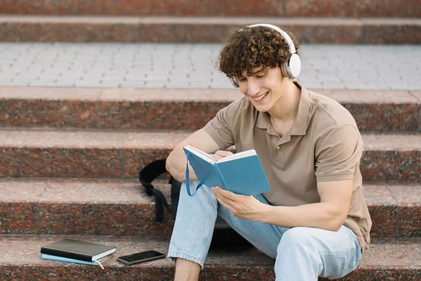 Ελκυστικός Μαθητής Κάθεται Στα Σκαλιά Του Πανεπιστημίου Και Διαβάζει Κάτι — Φωτογραφία Αρχείου