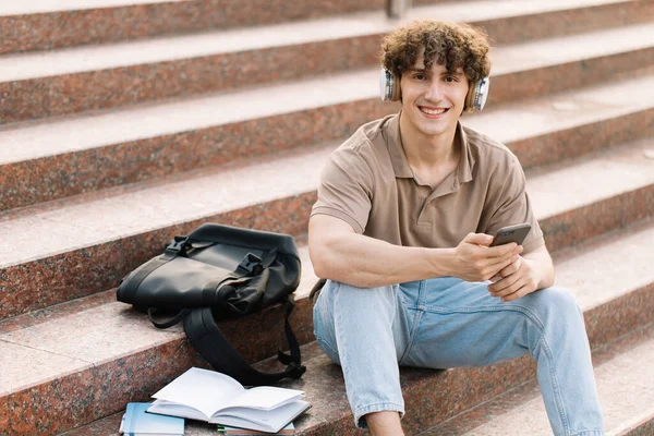 Çekici Kıvırcık Saçlı Genç Adam Üniversite Üniversite Öğrencisi Merdivenlerde Oturuyor — Stok fotoğraf