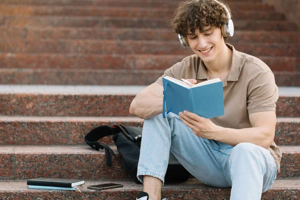 Ελκυστικός Μαθητής Κάθεται Στα Σκαλιά Του Πανεπιστημίου Και Διαβάζει Κάτι — Φωτογραφία Αρχείου