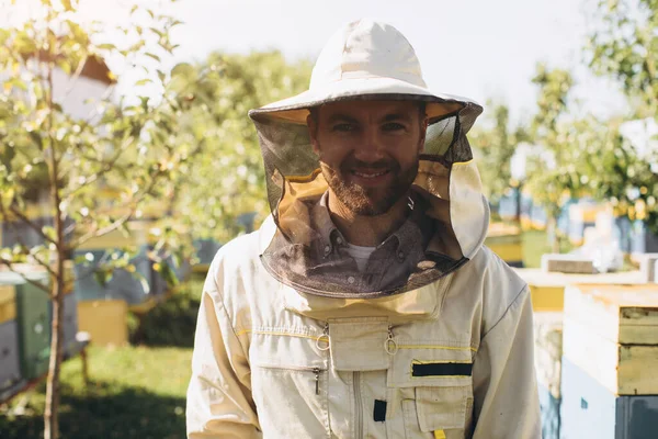 ミツバチの巣の近くの養蜂場で働く幸せなオスの養蜂家の肖像画 蜂蜜を集めろ 養蜂家の仕事だ 養蜂の概念 — ストック写真